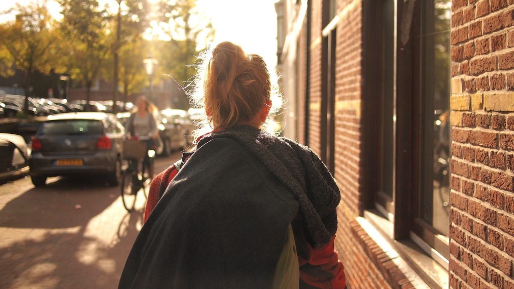 woman walking away from viewer down an suburban street