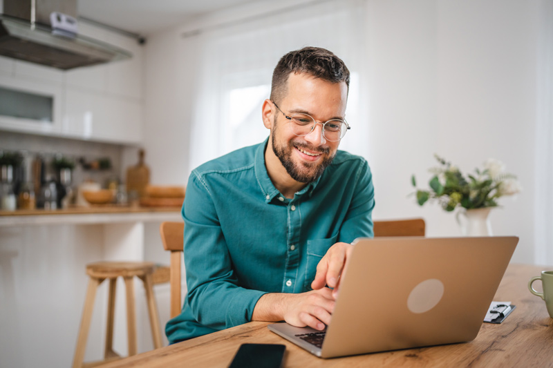 a man looking at his computer at home on a tabletop